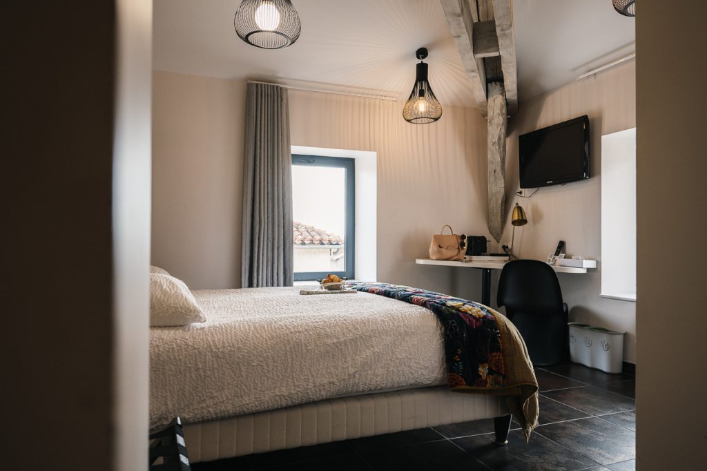Chambre confortable située au troisième étage de l'Hôtel Les Fleurines, sous les combles, avec une belle literie et un édredon coloré. Depuis cette chambre, profitez d'une vue imprenable sur les toits pittoresques de Villefranche-de-Rouergue, dans l'Aveyron. Un cadre cosy pour une expérience authentique.