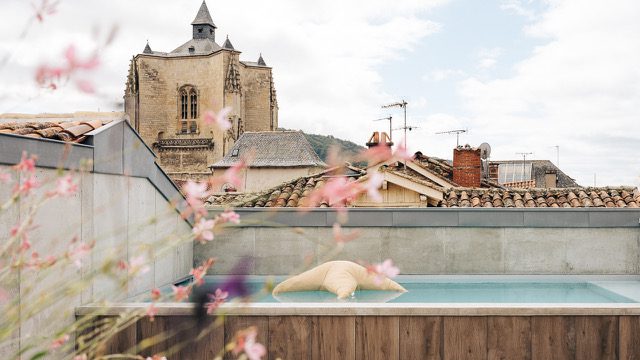 Plongez dans la détente sur le rooftop avec piscine de l’Hôtel Les Fleurines à Villefranche-de-Rouergue, tout en profitant de la vue imprenable sur la Collégiale Notre-Dame et les toits pittoresques de la bastide, en Aveyron.