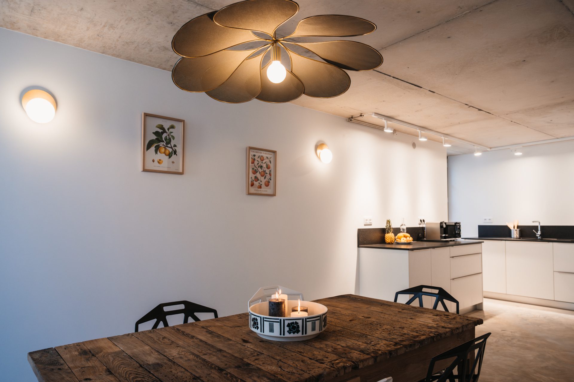 Cuisine de la Maison des Cassiers, au sein de l’Hôtel Les Fleurines à Villefranche-de-Rouergue, Aveyron. Entre son style moderne et son charme authentique, cette pièce se distingue par une vieille table en bois, parfaite pour des repas conviviaux, et des affiches d’agrumes au mur qui ajoutent une touche colorée et chaleureuse.