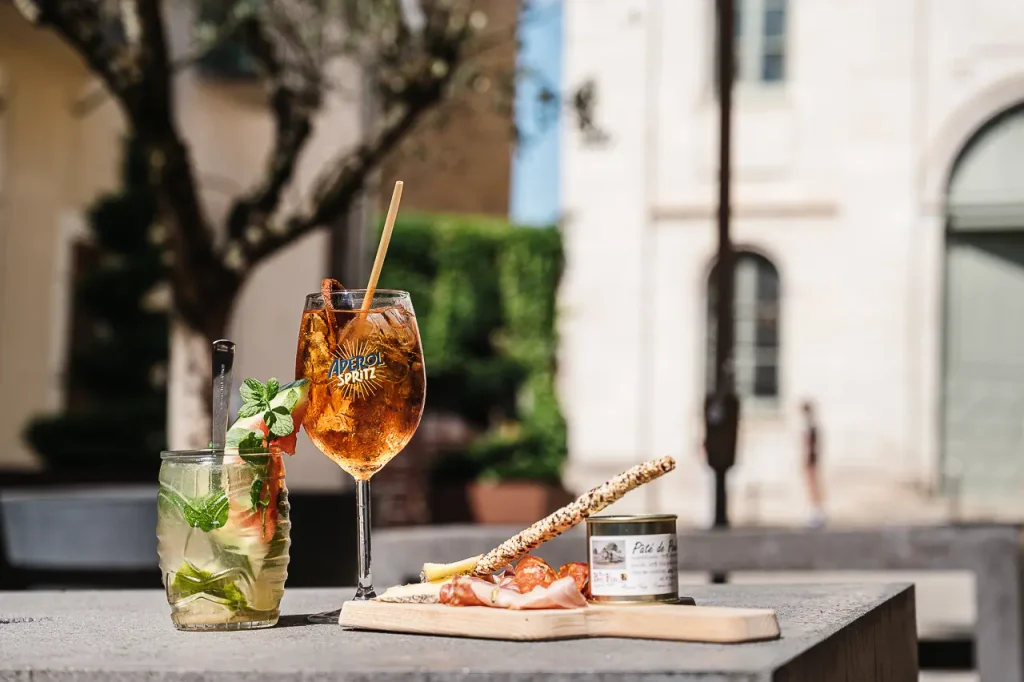Cocktails et planche de charcuterie et fromages en terrasse avec vue sur la chapelle des Pénitents noirs à Villefranche-de-Rouergue - Hôtel Les Fleurines, Aveyron